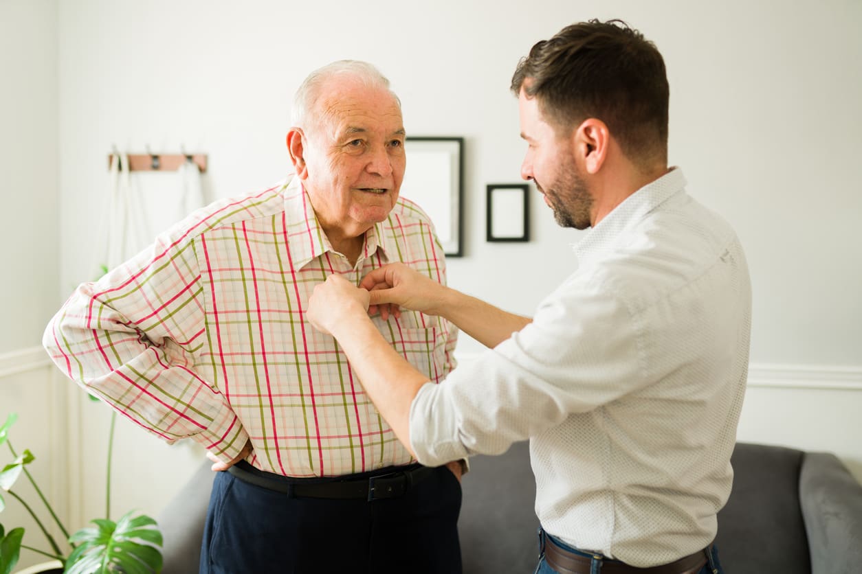 7 Signs It’s Time for Memory Care for Your Loved One young man helping older man with shirt