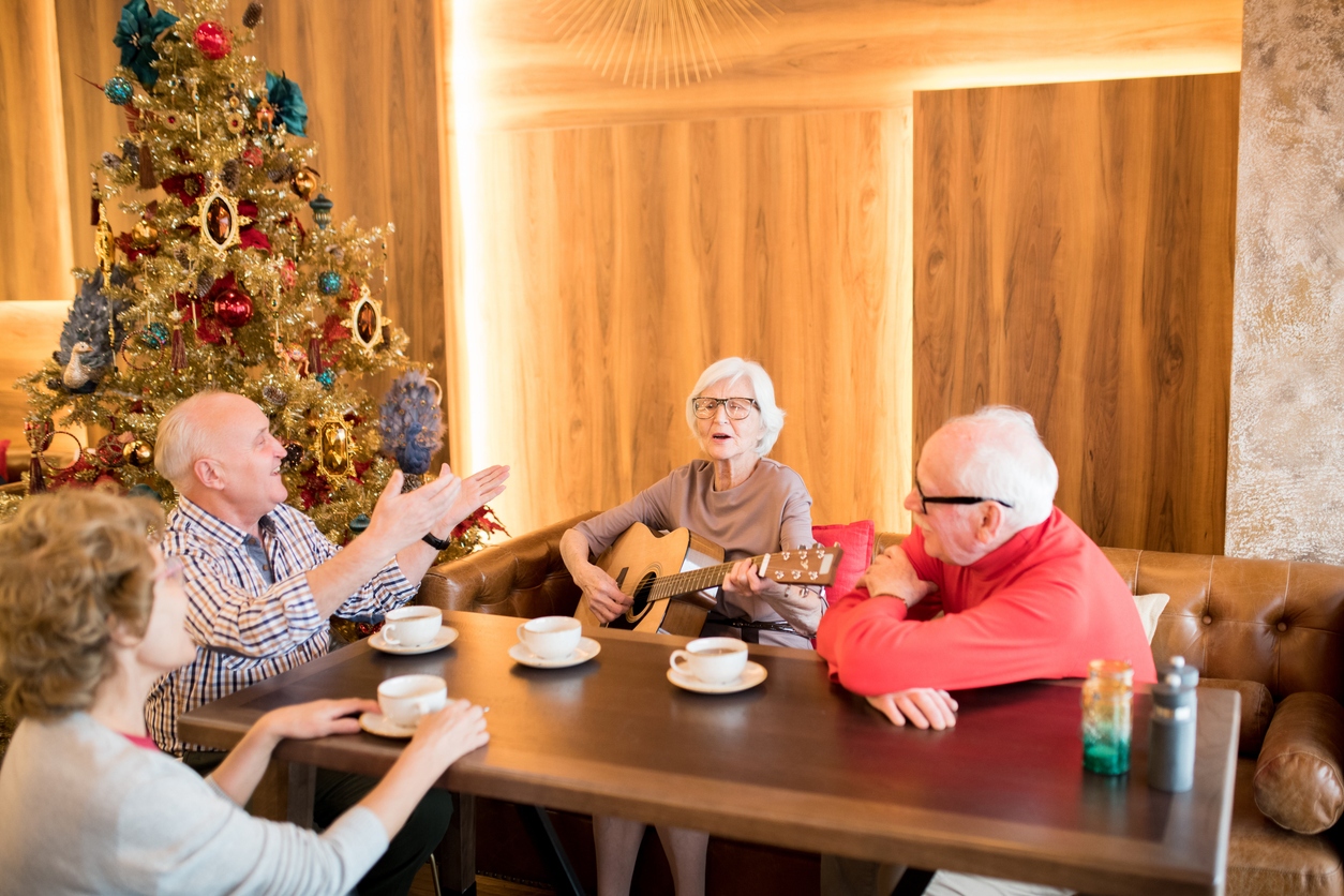 Elderly lady playing guitar at Christmas party How Holiday Activities for Assisted Living Residents